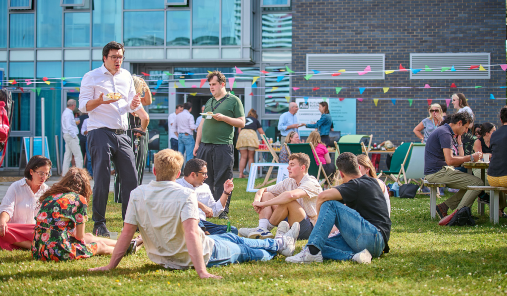 External pic of cambridge campus building 1 on our summer party - multiple people sitting outside